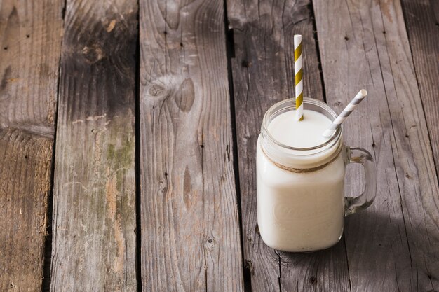 Elevated view of milk jar with two drinking straws on wooden table