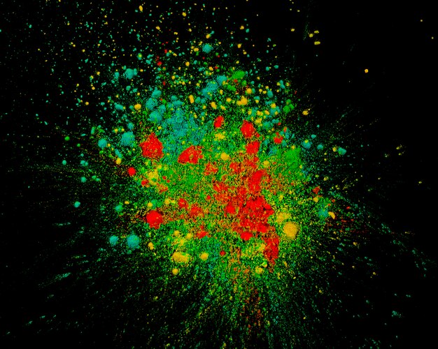Повышенный вид смешанных цветов Холи, взрывающихся на темном фоне