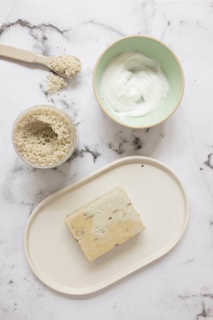 Elevated view of moisturizing cream; soap and salt on marble background