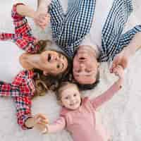 Free photo elevated view of mother; daughter and father lying on white fur