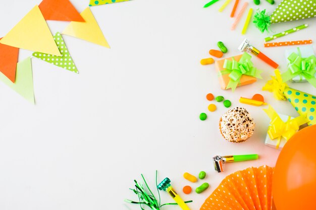 Elevated view of muffins; gift box; candies and party accessories on white backdrop