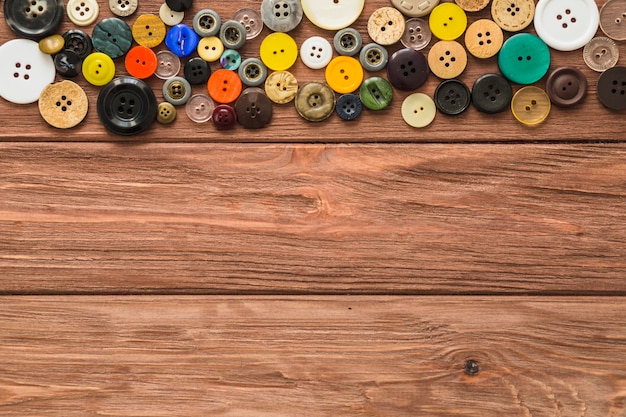 Foto gratuita vista elevata di multi bottoni colorati su fondo di legno