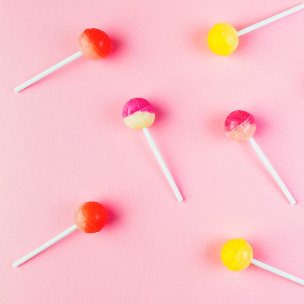 Elevated view of multi colored lollipops on pink backdrop