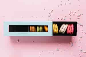 Бесплатное фото Повышенные вид красочных миндальное печенье в коробке на розовом фоне