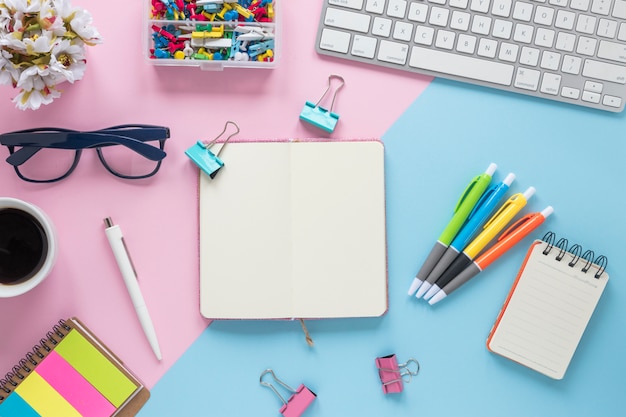 An elevated view of office supplies on dual pink and blue background