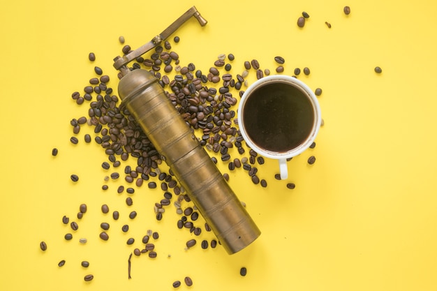 Free photo elevated view of old coffee grinder and coffee beans with hot coffee on colored backdrop