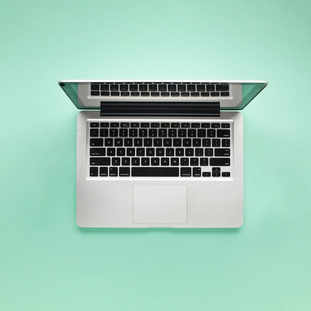 Elevated view of open laptop on green background