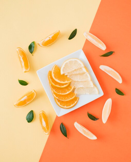 An elevated view of an orange and lemon slices on plate over the dual backdrop