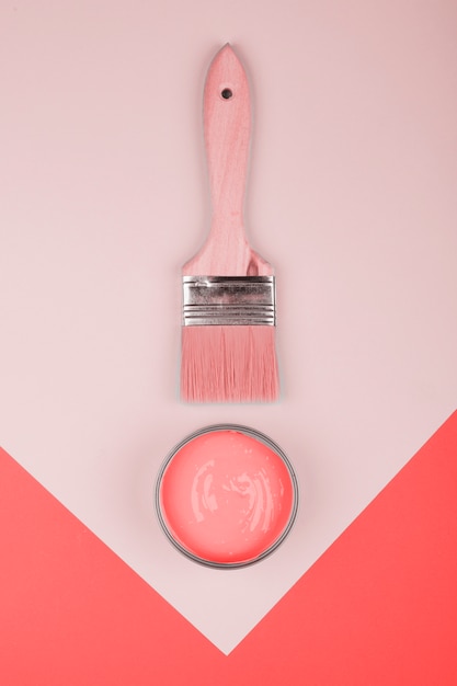 An elevated view of paintbrush and coral paint on geometric paper background