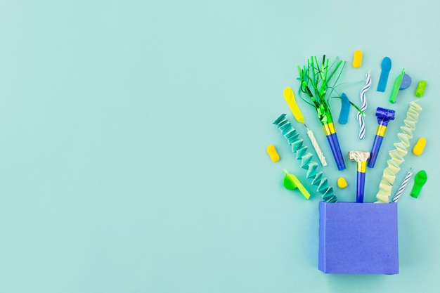 Elevated view of paper bag with birthday accessories on green background