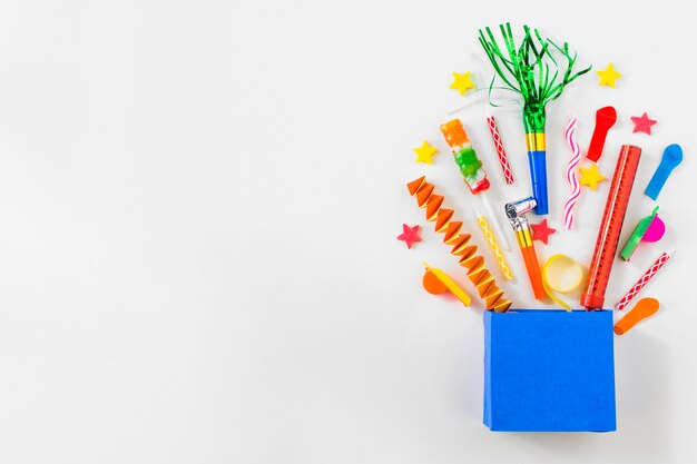 Elevated view of paper bag with various party accessories on blue background