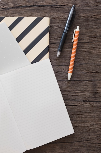 Elevated view of pen; notebook on wooden desk