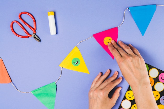 Elevated view of person hand sticking emoji sticker on bunting