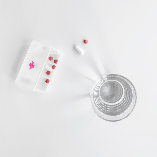 Elevated view of pills box near glass of water