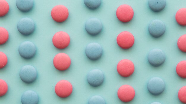 Elevated view of pink and blue candies in a row on green backdrop