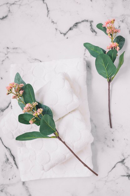 Elevated view of pink flowers and white napkins on marble surface