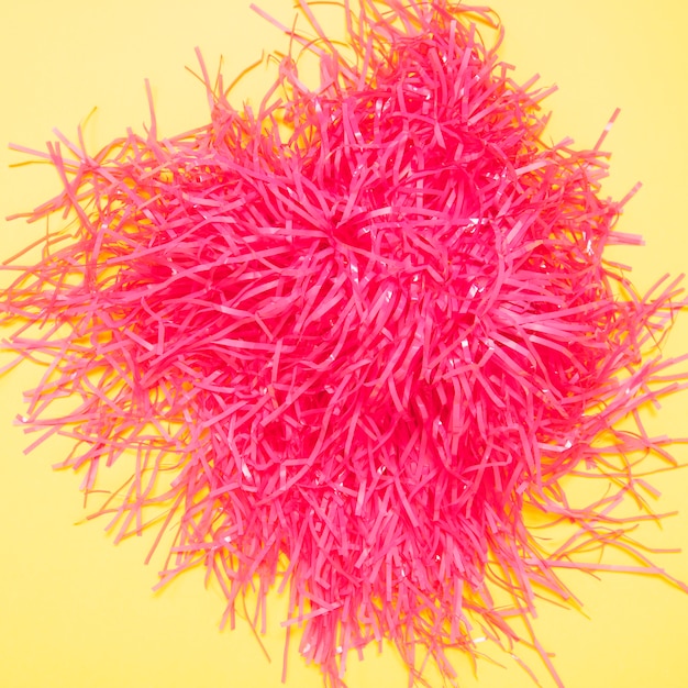 An elevated view of pink pom pom on yellow background