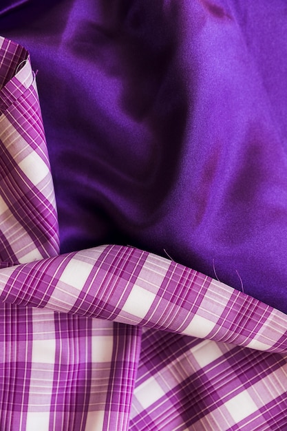 Elevated view of plaid textile on plain purple fabric material