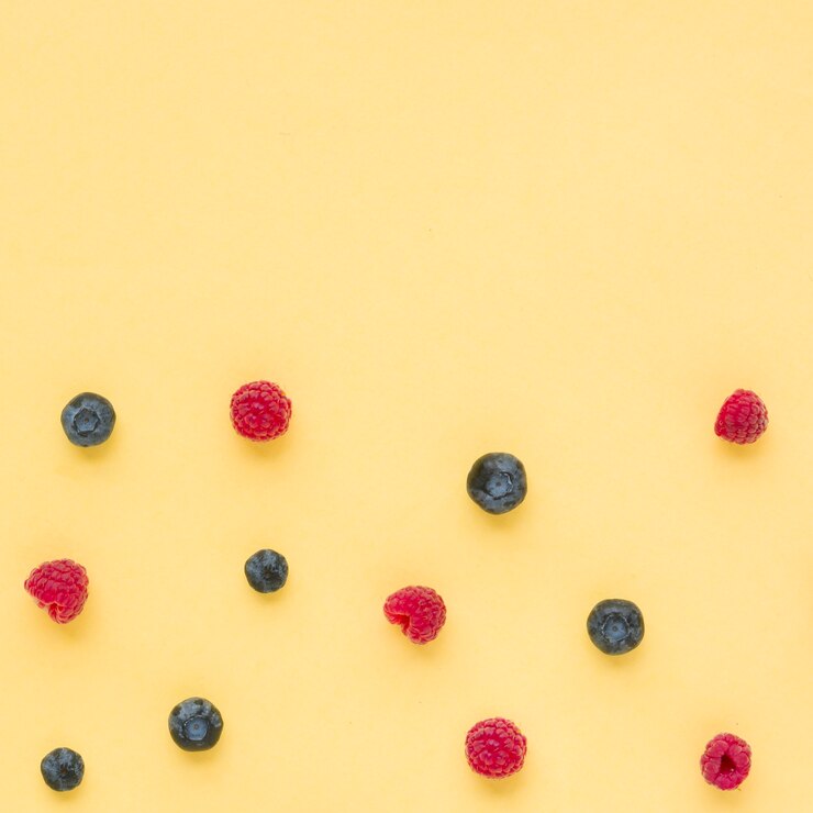 Free Photo an elevated view of raspberries and blueberries on yellow background