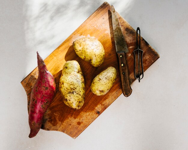 Free photo elevated view of raw potatoes on wooden chopping board