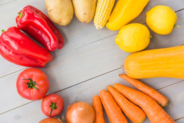 Elevated view of raw vegetables forming frame on wooden background