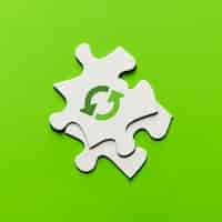 Free photo elevated view of recycling icon on white puzzle piece over green backdrop