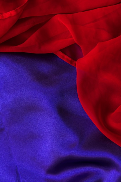 Elevated view of red chiffon textile on plain blue cloth