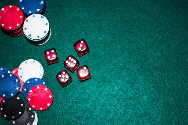 Elevated view of red dices and casino chips on green poker table