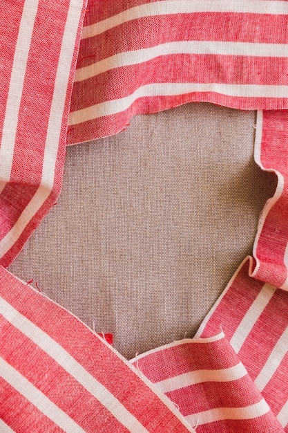 Elevated view of red and white stripes fabric material on plain sack cloth