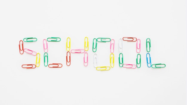 Free photo elevated view of school word made up of colorful paper clips on white backdrop