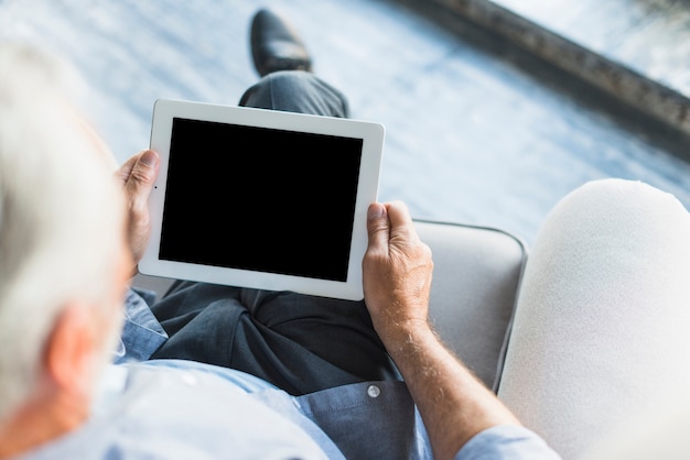 空の画面でデジタルタブレットを見て上級男性の高められたビュー