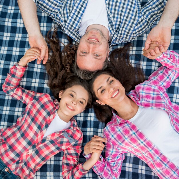 Elevated view of smiling family lying on checkered blanket