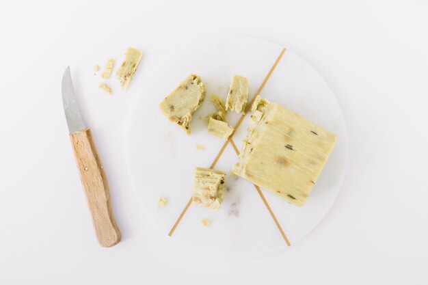 Elevated view of soap on marble board near knife over white background