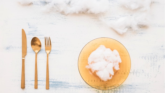 Elevated view of soft cotton on plate with utensils