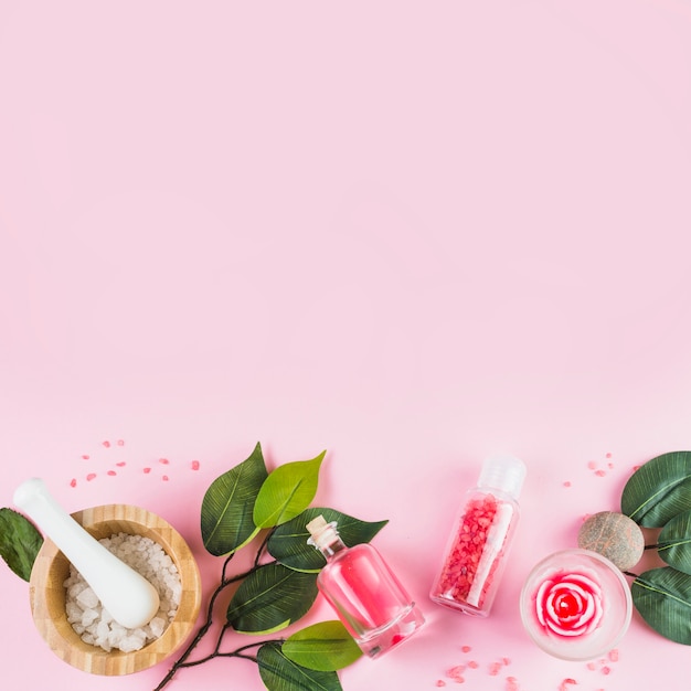 Elevated view of spa products and leaves at the bottom of pink surface