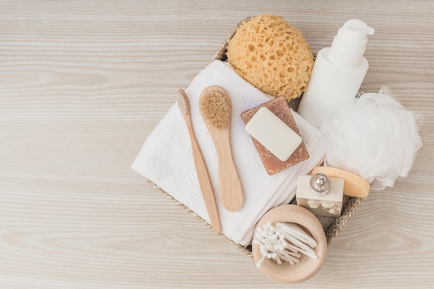 Free photo elevated view of spa products with brushes and loofah in tray on wooden surface