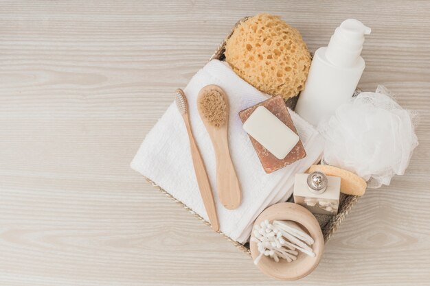 Elevated view of spa products with brushes and loofah in tray on wooden surface