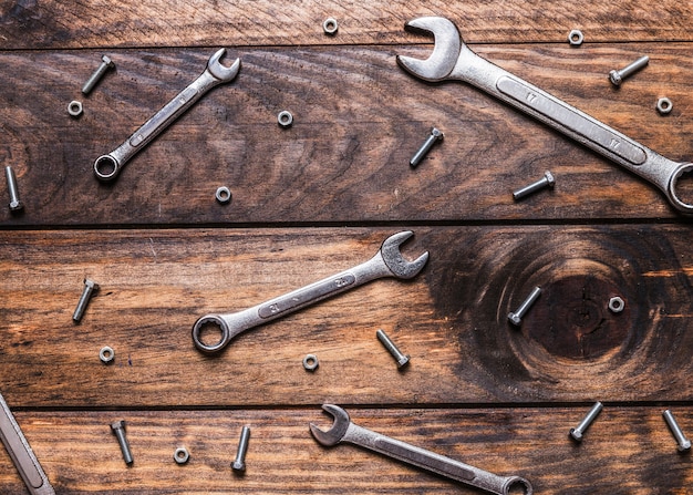 Elevated view of spanners and screws on wooden background