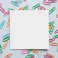 Free photo elevated view of square shaped cardboard paper and many paper clips on grey background