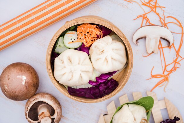 An elevated view of steam dumplings and salad in bamboo steamer