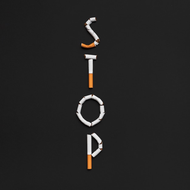 Elevated view of stop word made from cigarette above black backdrop