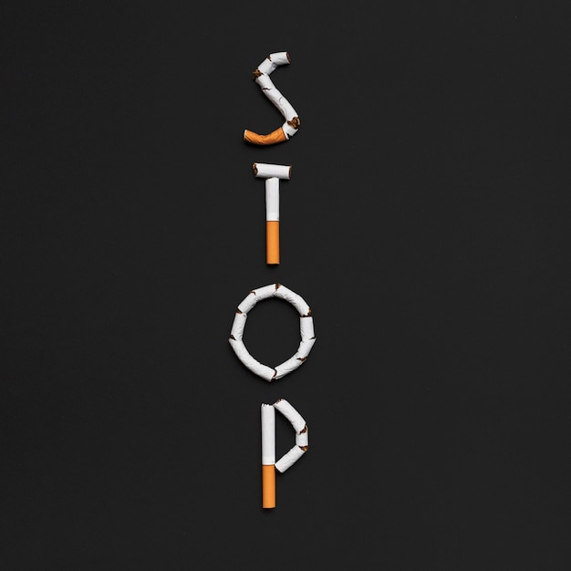 黒い背景上のタバコから作られたストップワードの立面図