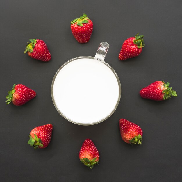 Elevated view of strawberries and milk on black background