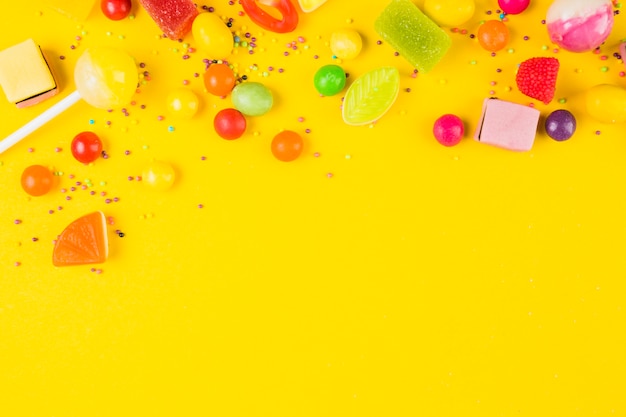 Elevated view of sweet candies on yellow backdrop