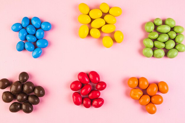 Elevated view of sweet colorful candies on pink backdrop