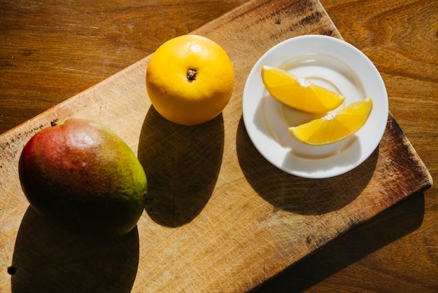 Elevated view of sweet lime and mango on chopping board