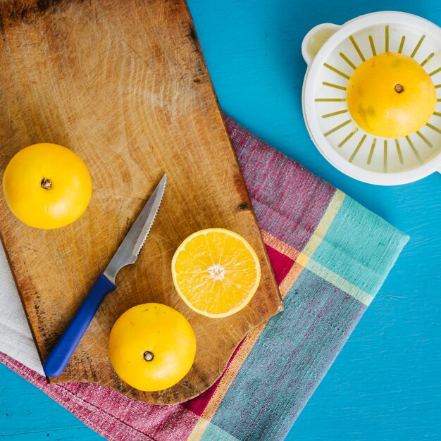 Elevated view of sweet limes and manual juicer on blue backdrop