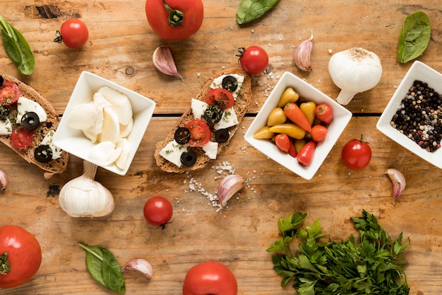 Elevated view of tasty bruschetta and fresh italian ingredients over table