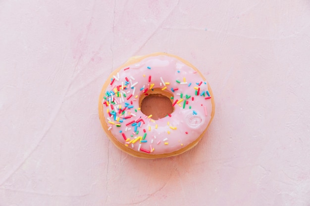 Elevated view of tasty donut with sprinkle isolated on pink background