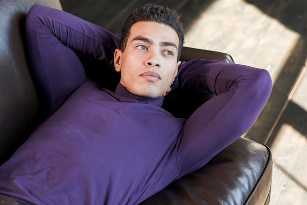 An elevated view of thoughtful young man lying on sofa
